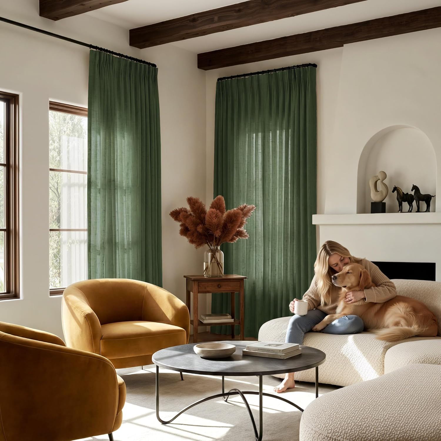 Sage green linen blend pleated curtains hang on a black rod in a bright, modern living room.