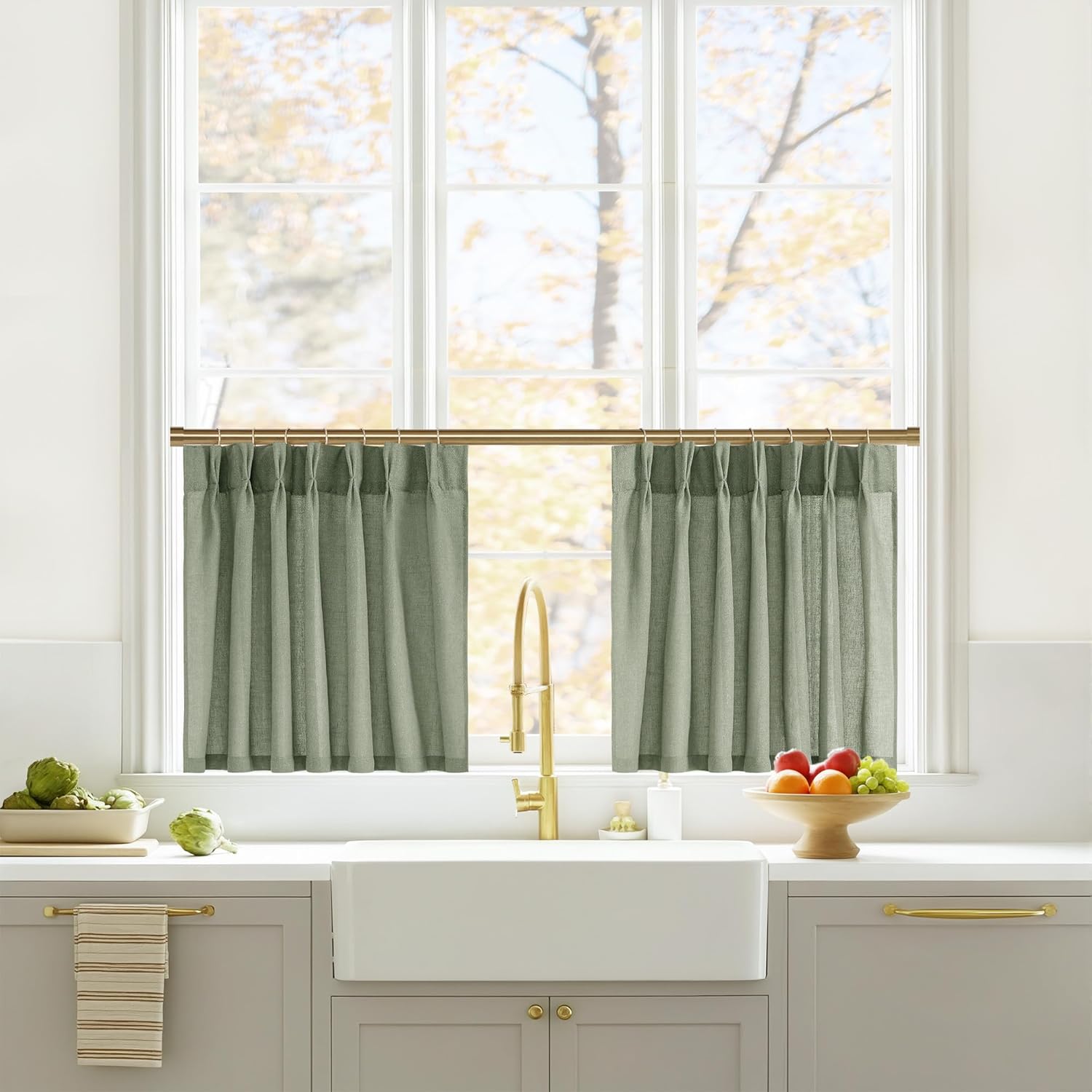 Two sage green linen look cafe curtains with rod pockets hanging above a kitchen sink window.