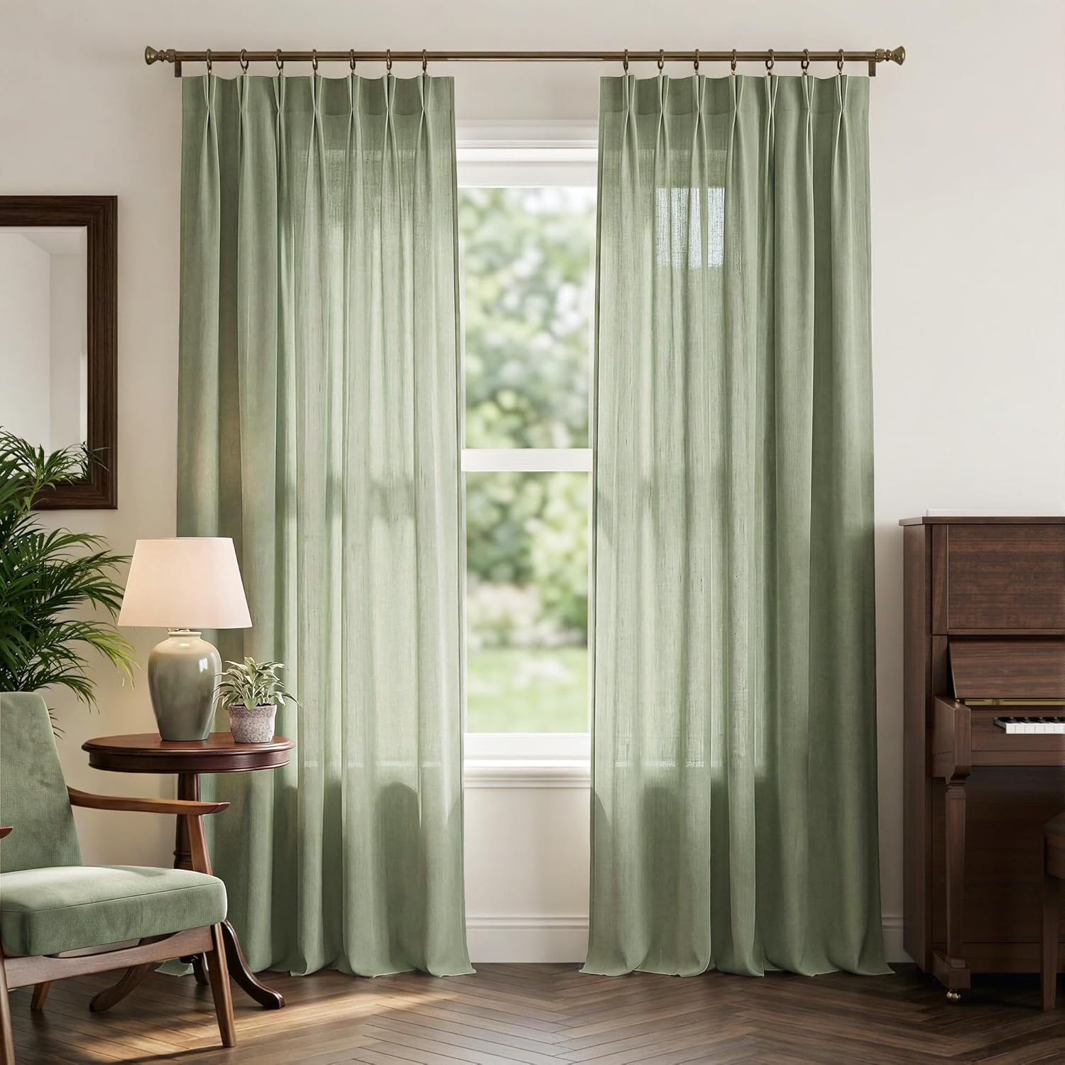 Pair of floor-length sage green linen pinch pleat drapes on a bronze rod, softly filtering sunlight.