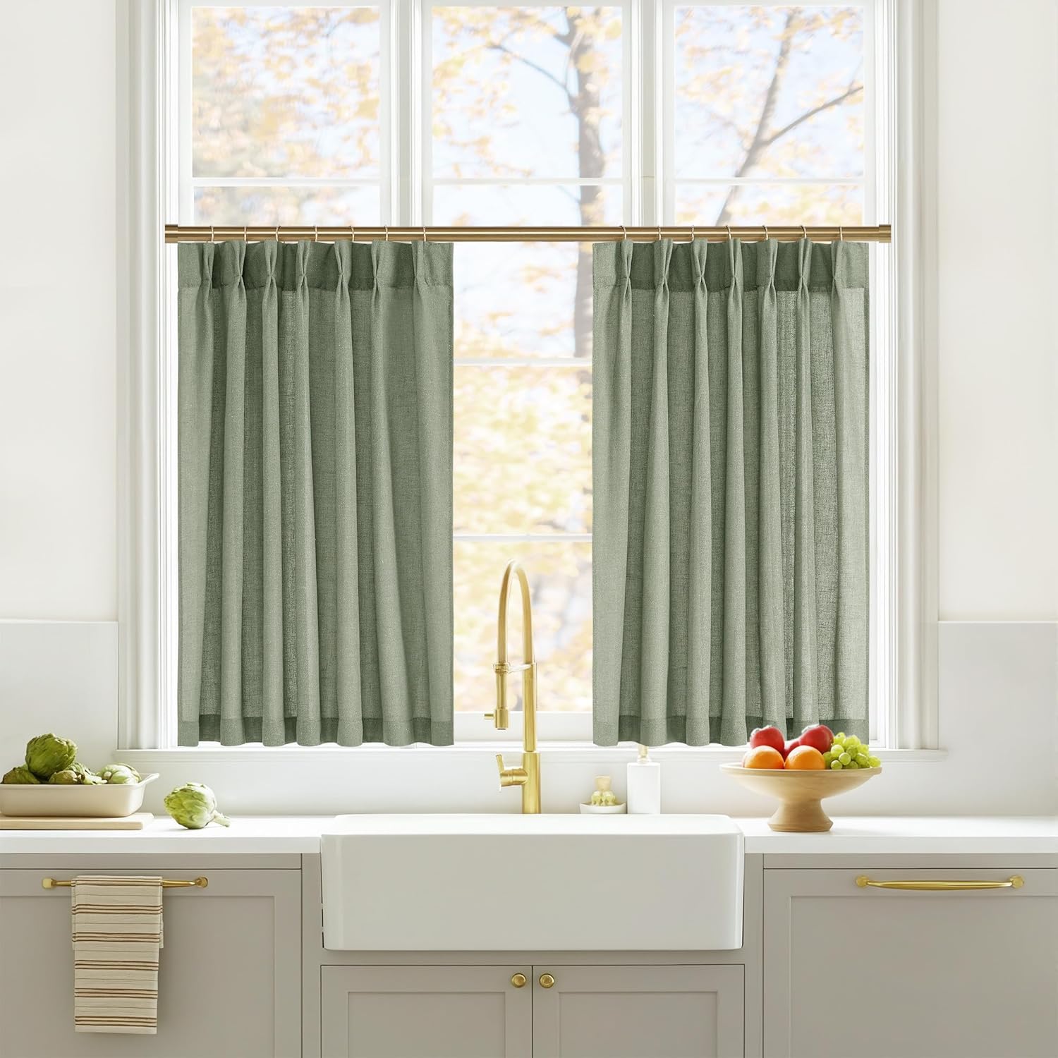 Textured sage green linen-look cafe curtains with gathered pleats on a brass rod above a kitchen window.