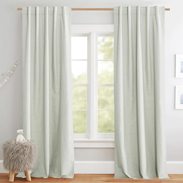 Full-length sage green linen textured curtains with back tab headers on a wooden rod.