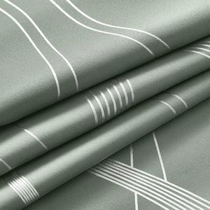 Detailed view of folded sage green fabric. Features silver metallic geometric lines and stripes on a textured surface.