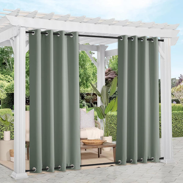 Sage green outdoor grommet curtains on black rods hang from a white pergola, providing patio privacy.