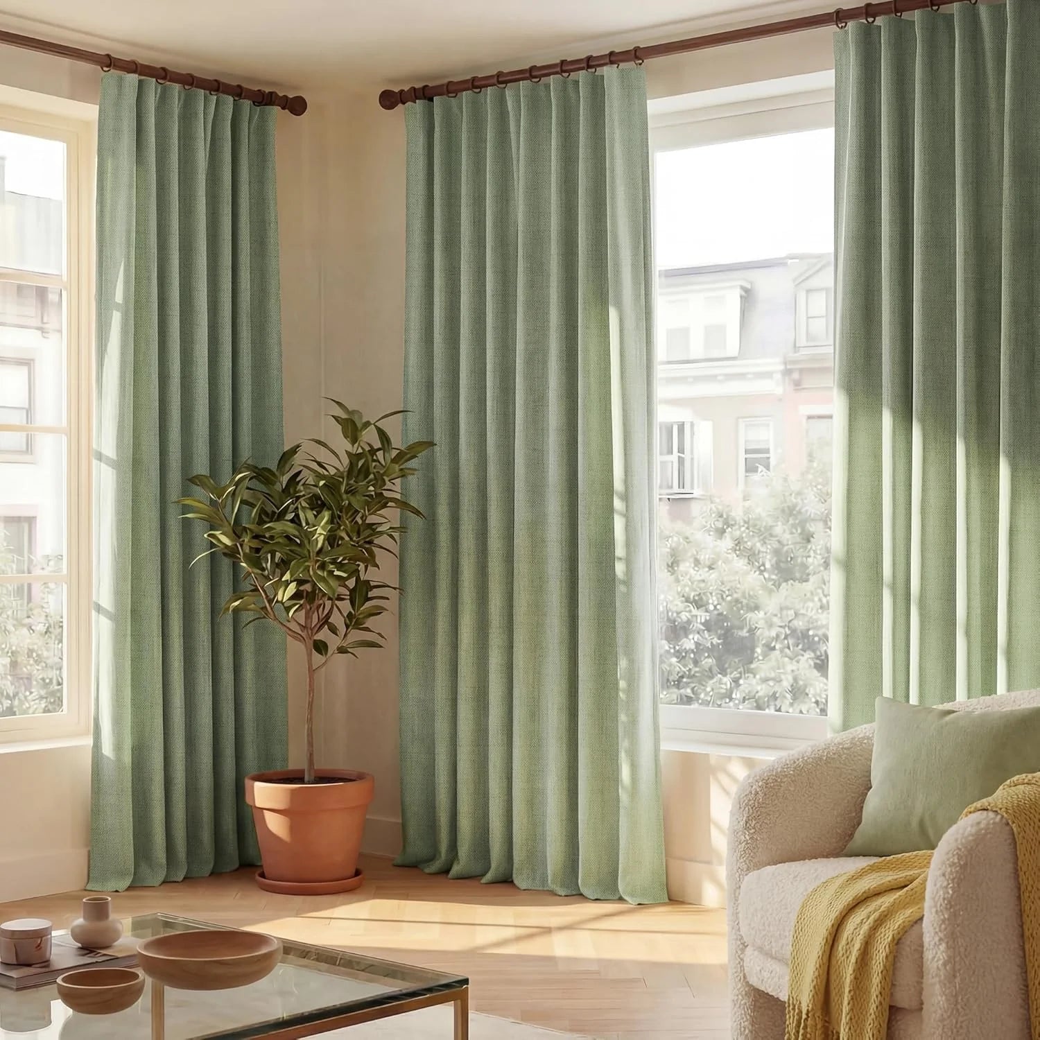 Sage green textured pleated curtains hanging by large windows in a bright modern living room.