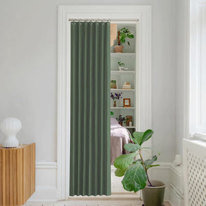 Dark sage green pleated doorway curtain with silver rings on a rod, separating a living space.