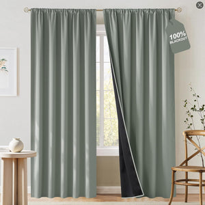 Sage green blackout curtains with a rod pocket top, showing the dark lining. Hung over a window.