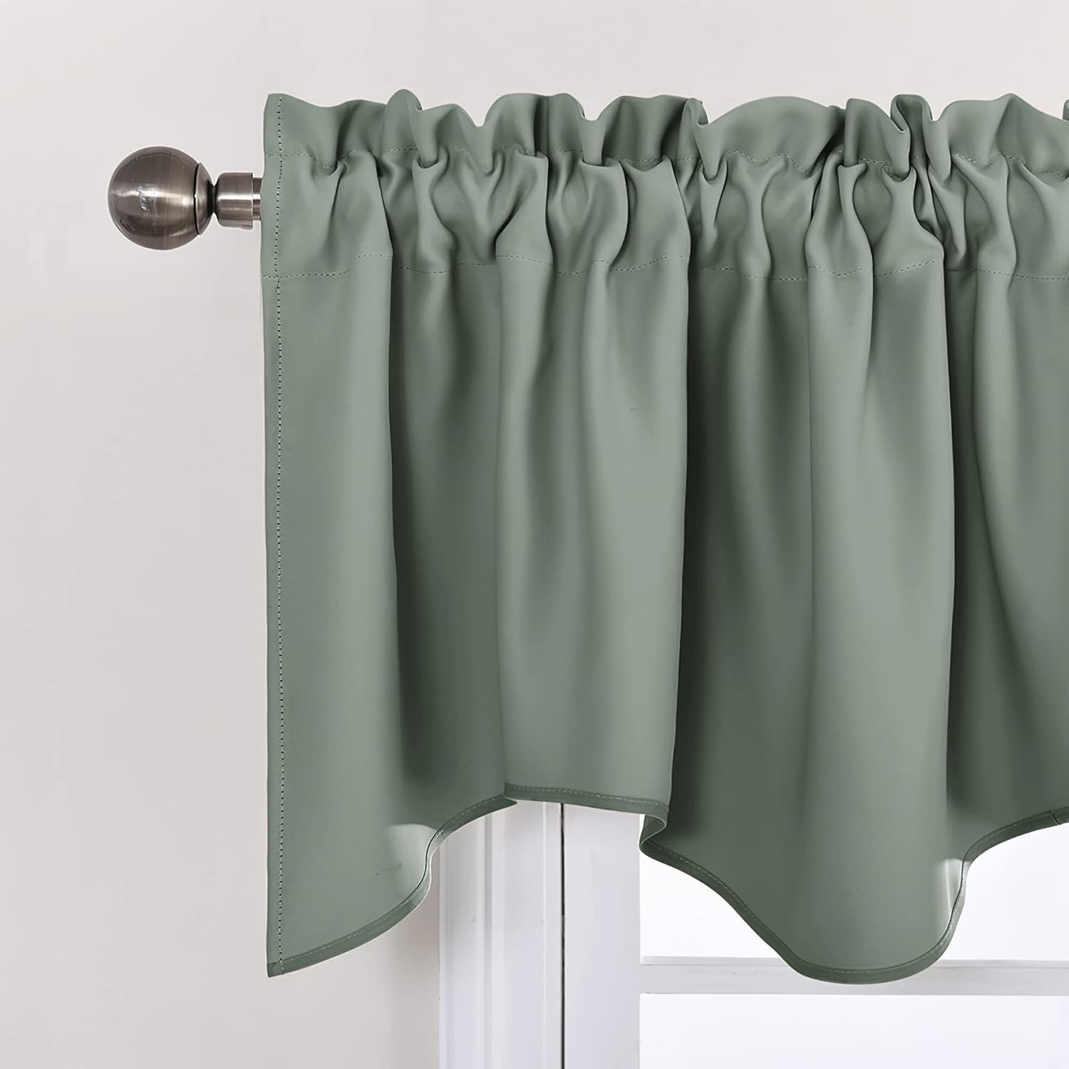 Sage green rod pocket window valance with a scalloped bottom edge, hanging on a decorative bronze rod.