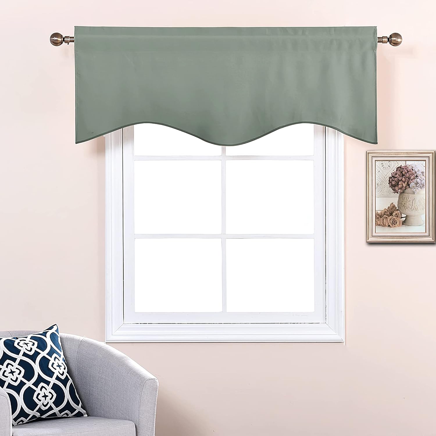 Sage green fabric window valance with a decorative scalloped bottom edge, hung on a bronze rod over a white window frame.