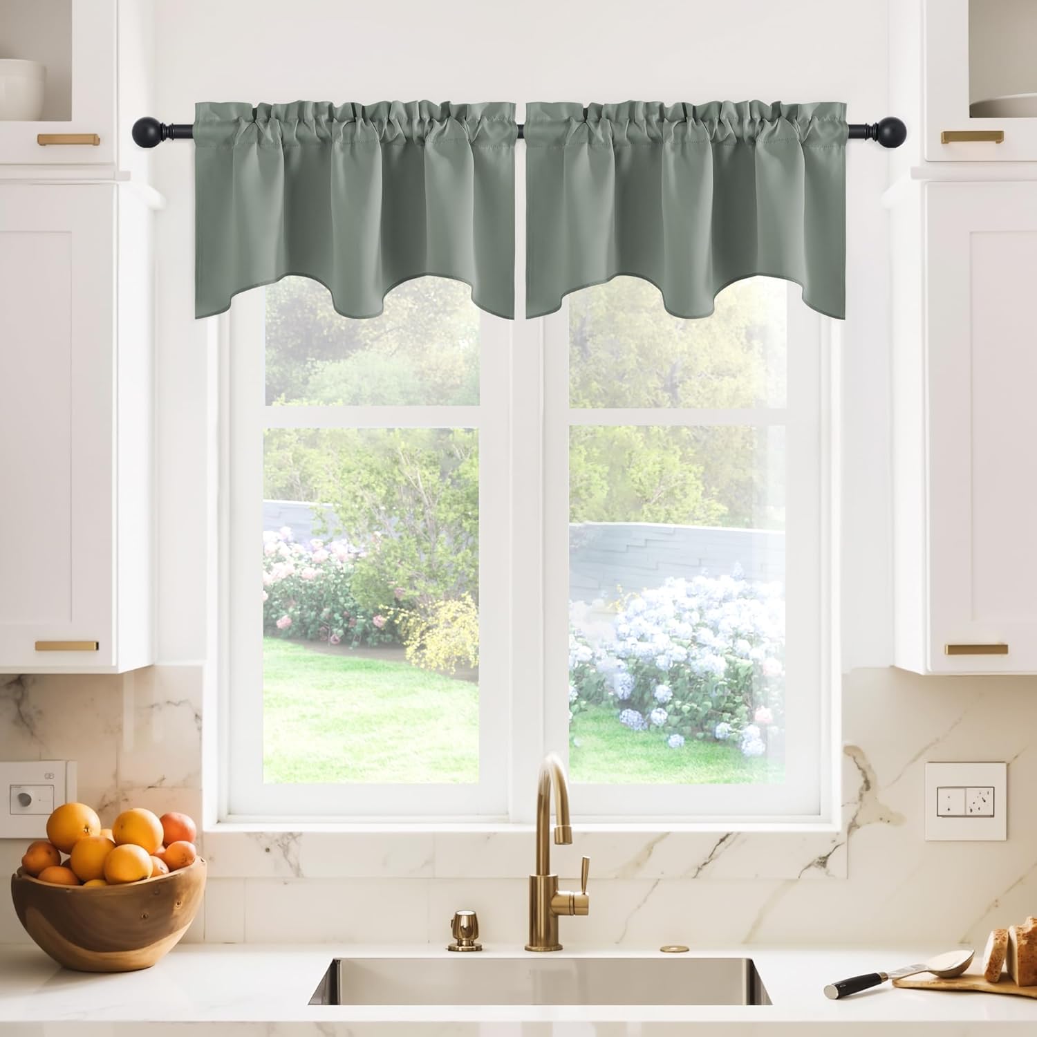 Sage green scalloped valance with a gathered top hanging on a black rod over a kitchen window.