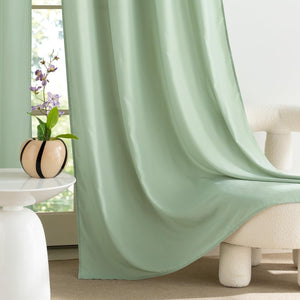 Sage green smooth fabric window curtains with soft folds, elegantly draped in a modern room setting.