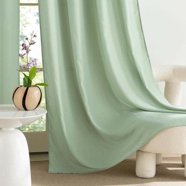 Sage green smooth fabric window curtains with soft folds, elegantly draped in a modern room setting.