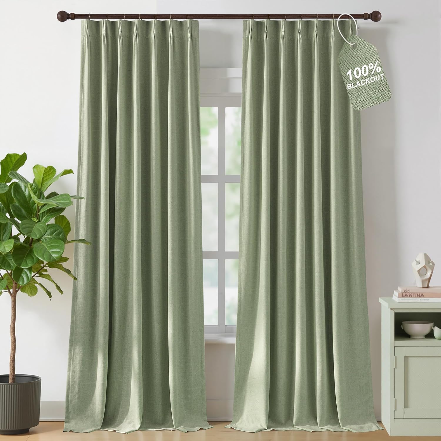 Muted sage green textured pinch pleat curtains, offering 100% blackout, hanging on a dark rod.