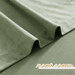 Close-up of soft, textured sage green velvet curtain fabric showing elegant folds and a neat seam.