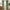 Long sage green velvet pinch pleat curtains hanging on a black rod, framing a window.