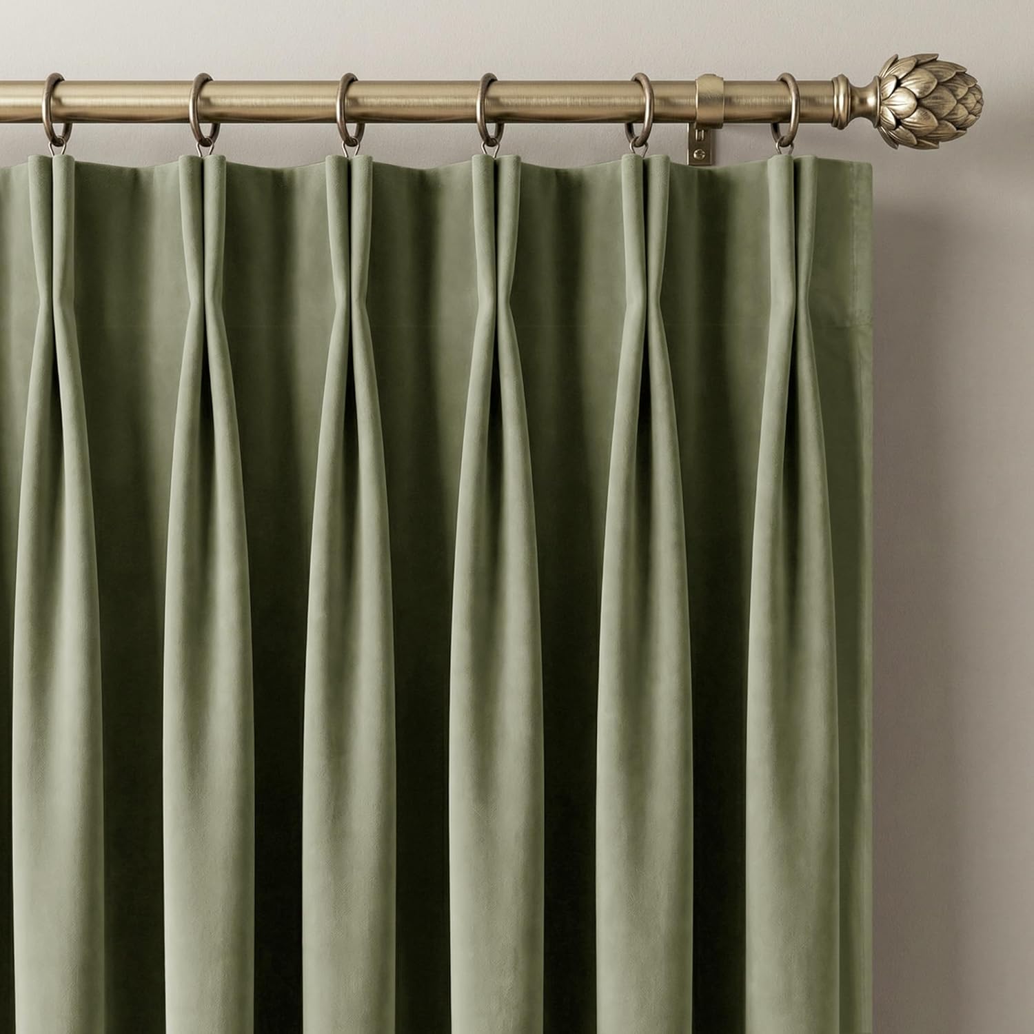 Elegant sage green velvet pinch pleat curtains on a brass rod with a decorative artichoke finial.