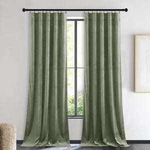 Two full length sage green velvet pinch pleat drapes hanging on a black rod over a window.