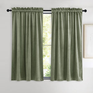 Pair of sage green velvet curtains with rod pocket top, hanging on a black rod.