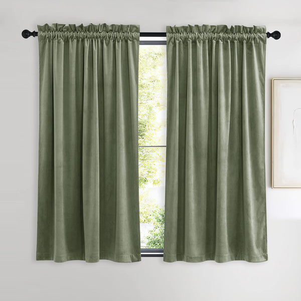 Pair of sage green velvet curtains with rod pocket top, hanging on a black rod.