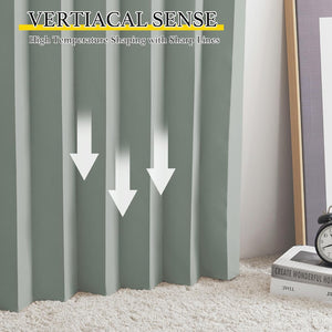Close-up of sage green drapes featuring sharp, structured vertical pleats, touching a cream shag rug.
