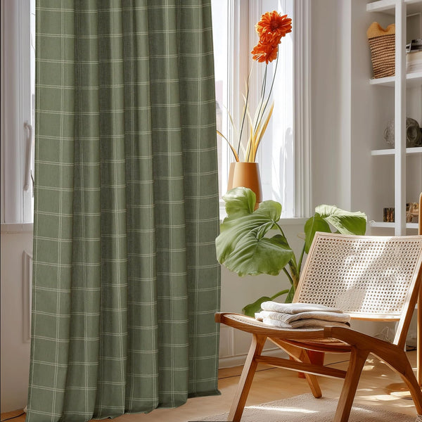 Sage green curtain panel featuring a white windowpane plaid pattern, hanging in a bright room.