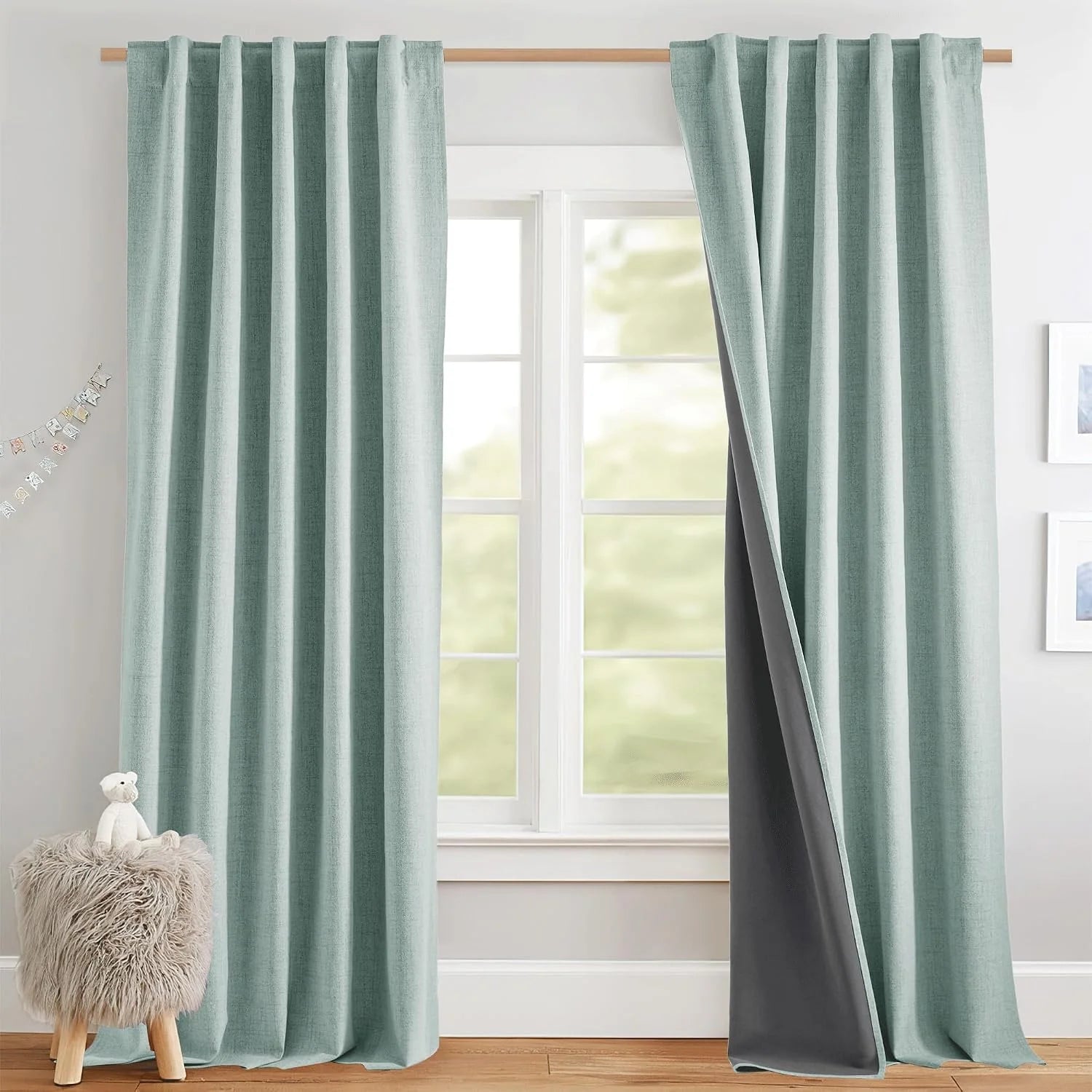 Soft sage textured blackout curtains on a wooden rod in a bright nursery window