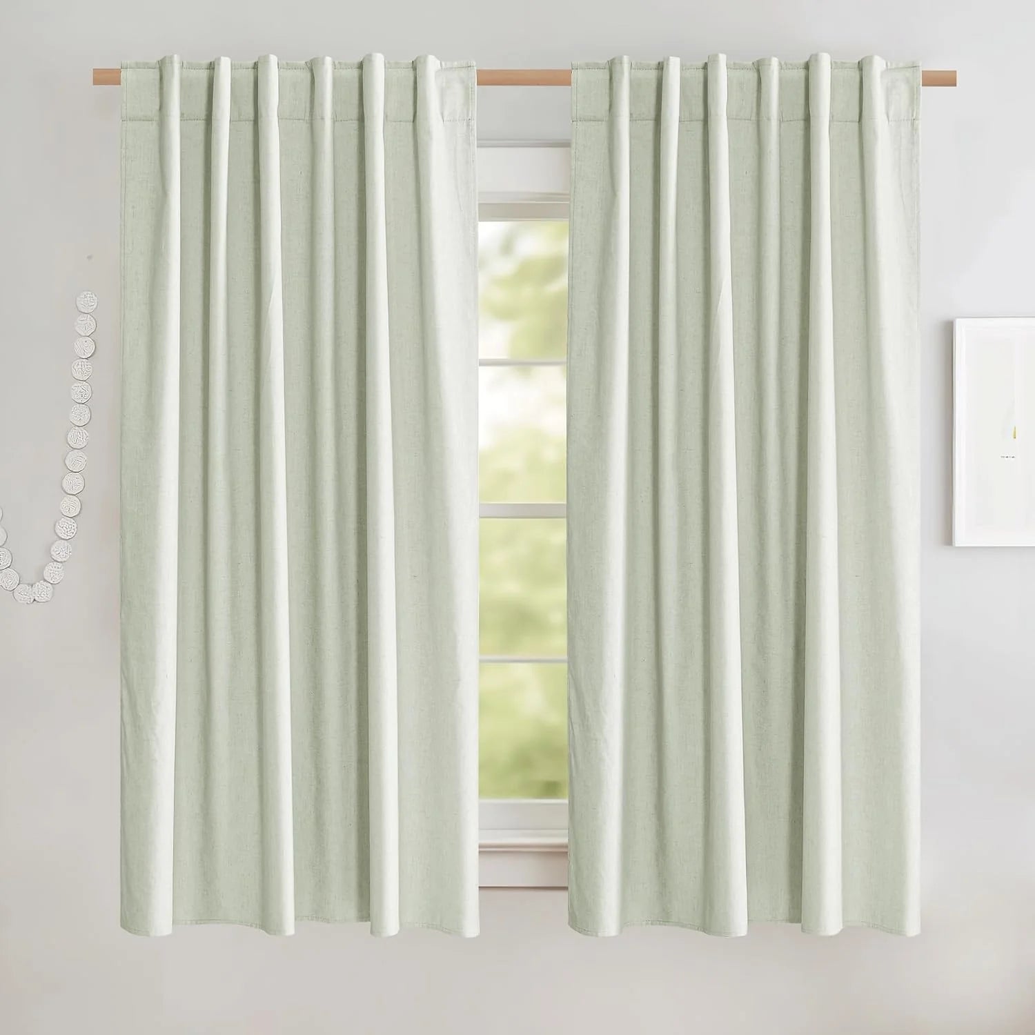 Soft sage green linen-look rod pocket curtains hanging on a wooden curtain rod