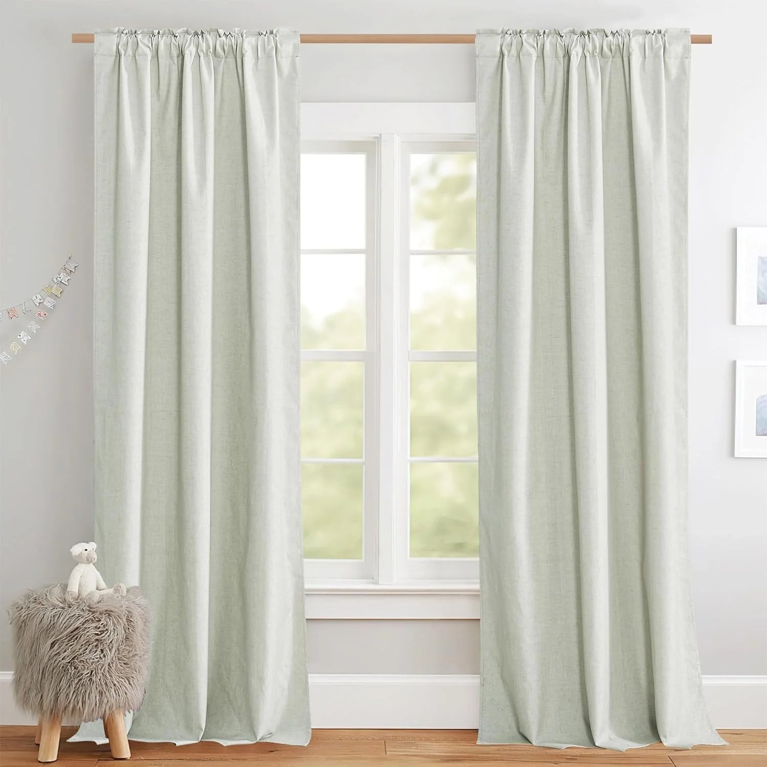 Soft sage linen-look rod pocket curtains hanging over a bright window in a cozy room