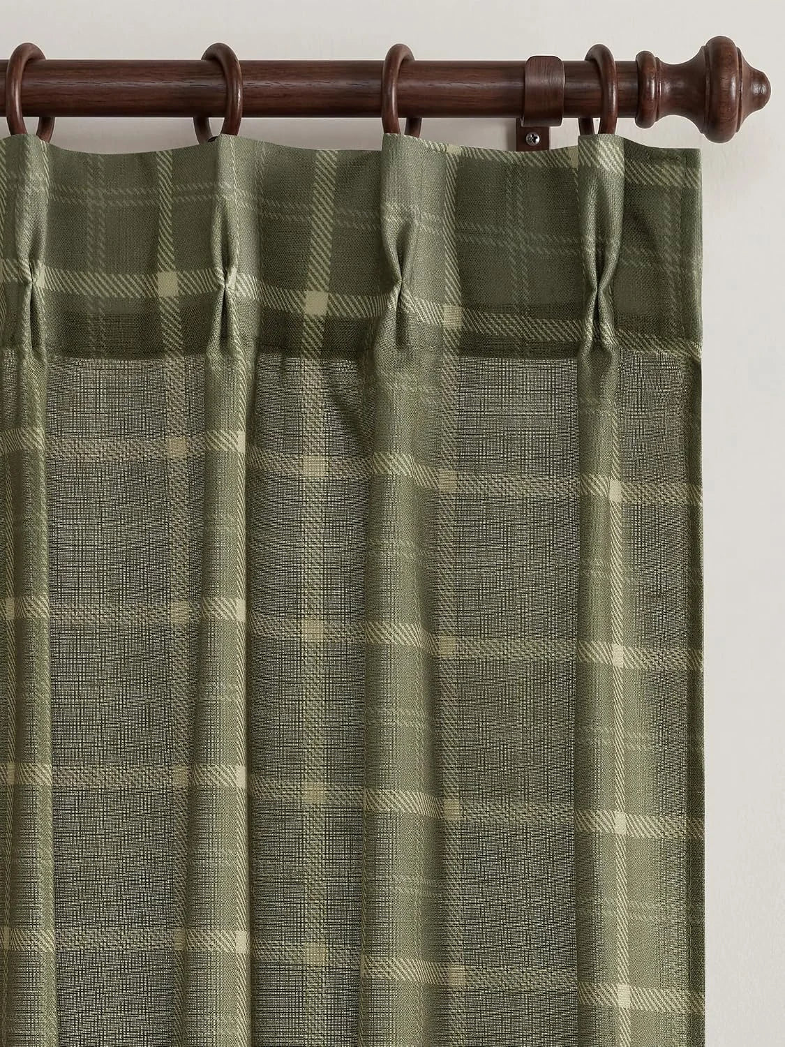 Sage green plaid curtain panel with tab top hanging on a dark wooden rod