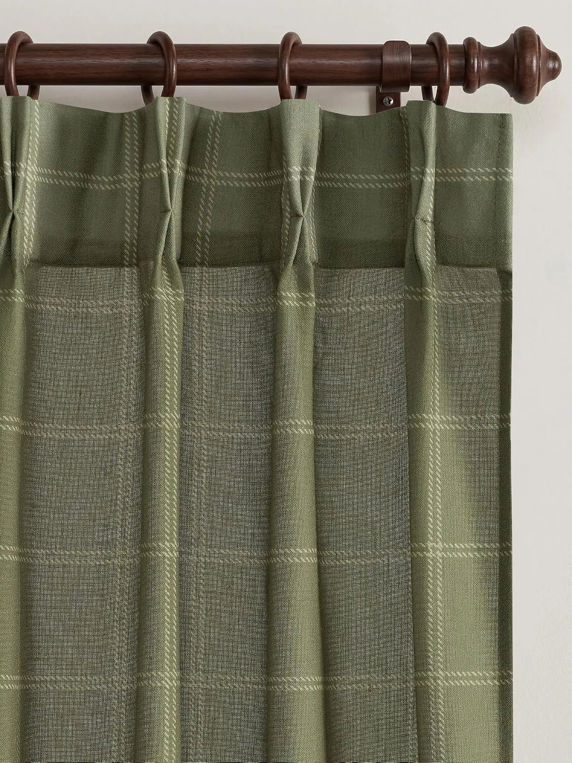 Sage green plaid tab top curtain hanging from a dark wooden rod