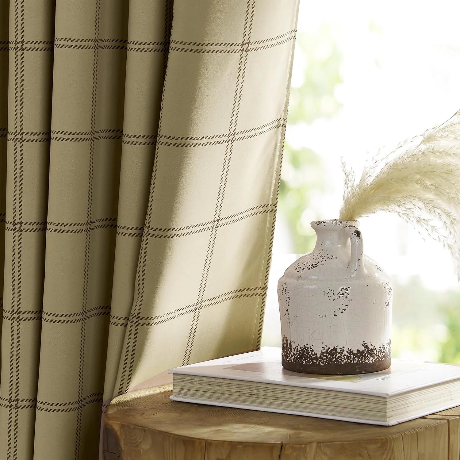 Sage green plaid curtain panel beside a rustic ceramic vase on a wooden table
