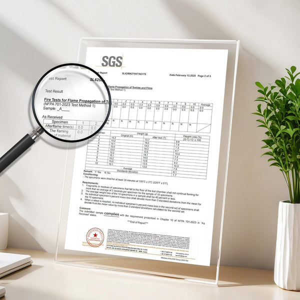 Close-up of an SGS fire safety test report for textiles, showing NFPA 701-2023 compliance, held in a clear acrylic display, with a magnifying glass.