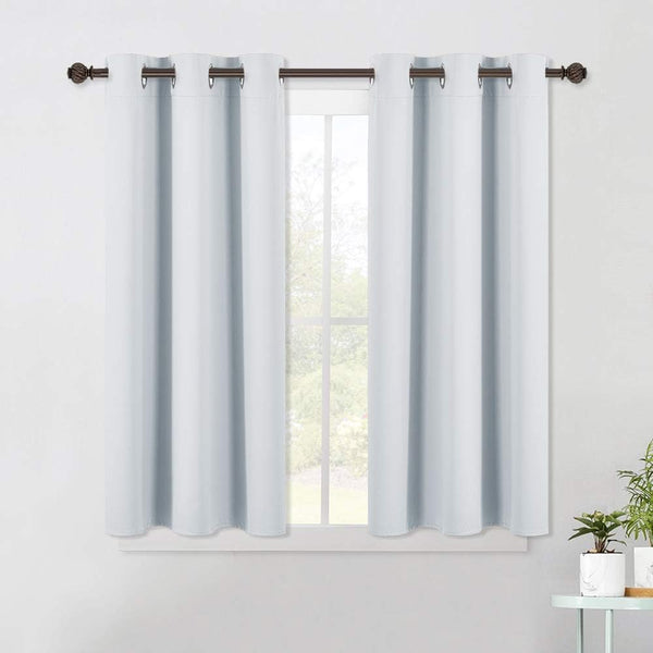 Two light blue short curtains with silver grommet tops on a dark rod, covering a bright window.