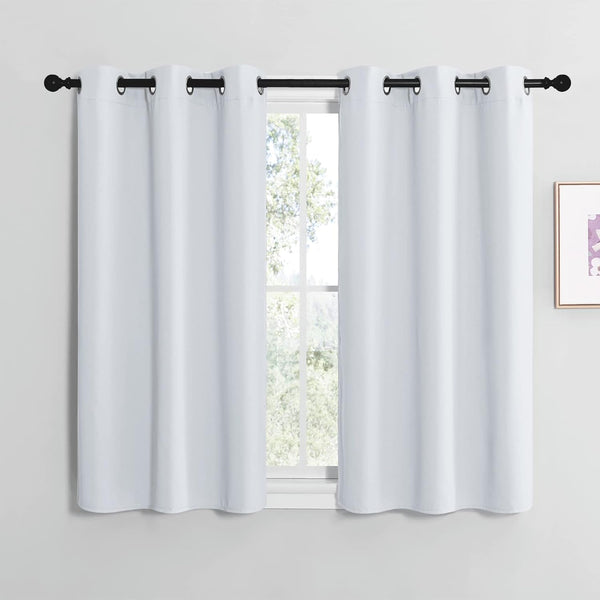 Pair of short white blackout curtains with dark metal grommets hanging on a black rod over a window.