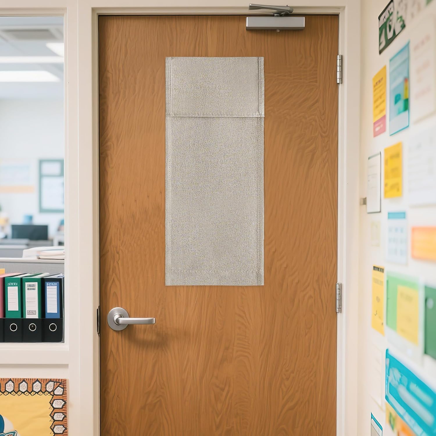 Silver textured privacy panel mounted on a wooden door window in a school or office hallway.