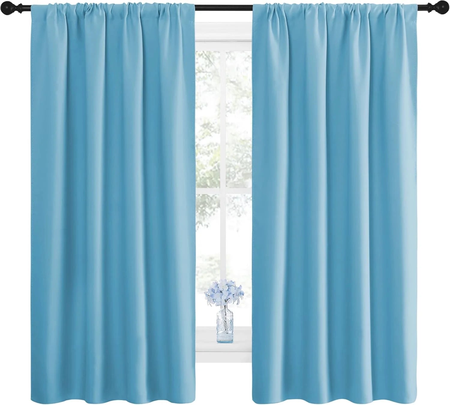 Sky blue rod pocket curtain panels hanging on a black rod over a bright window
