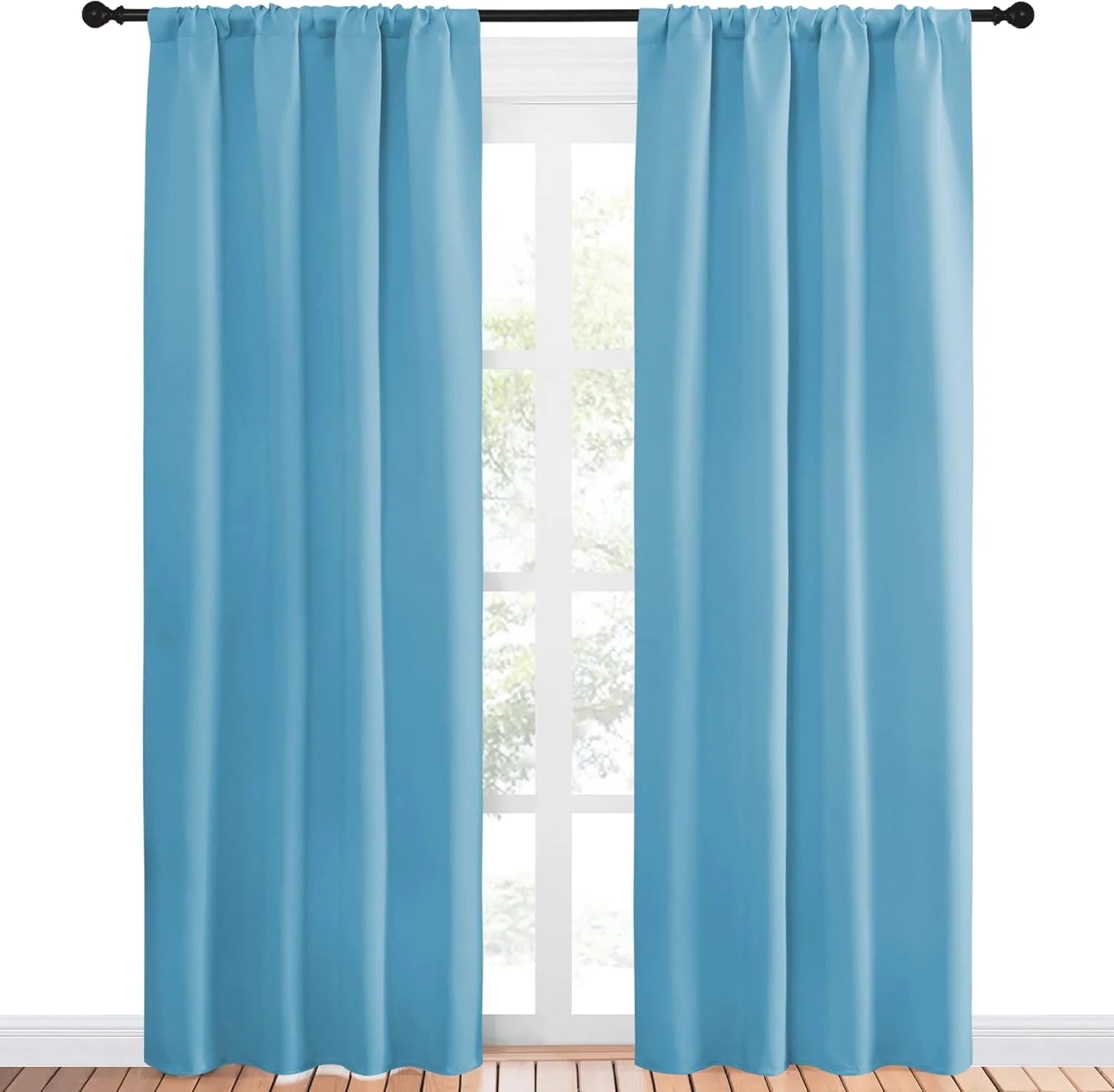 Sky blue solid rod pocket curtains hanging on a black curtain rod by a bright window