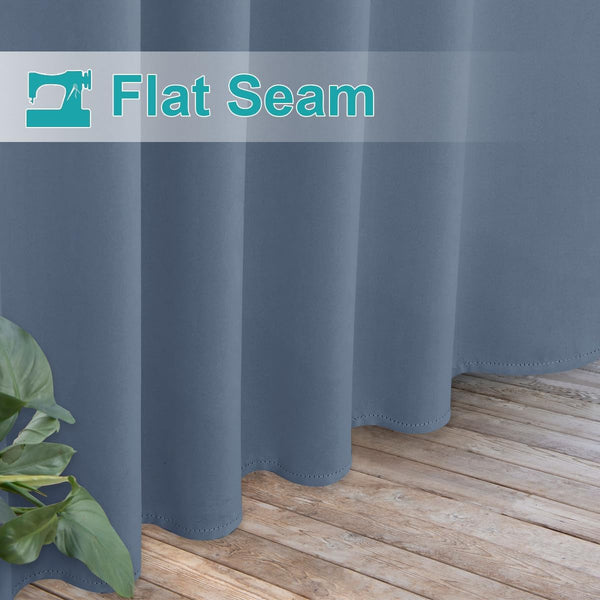 Close-up of slate blue curtains showcasing a neatly stitched flat seam hem, flowing to a light wooden floor.