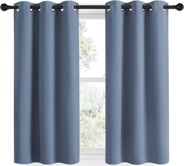 Pair of slate blue grommet top curtains hanging on a black rod over a window.