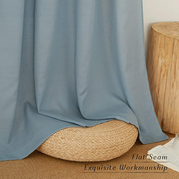 Soft slate blue curtain with a neatly visible flat seam, draped elegantly over a woven pouf in a home setting.