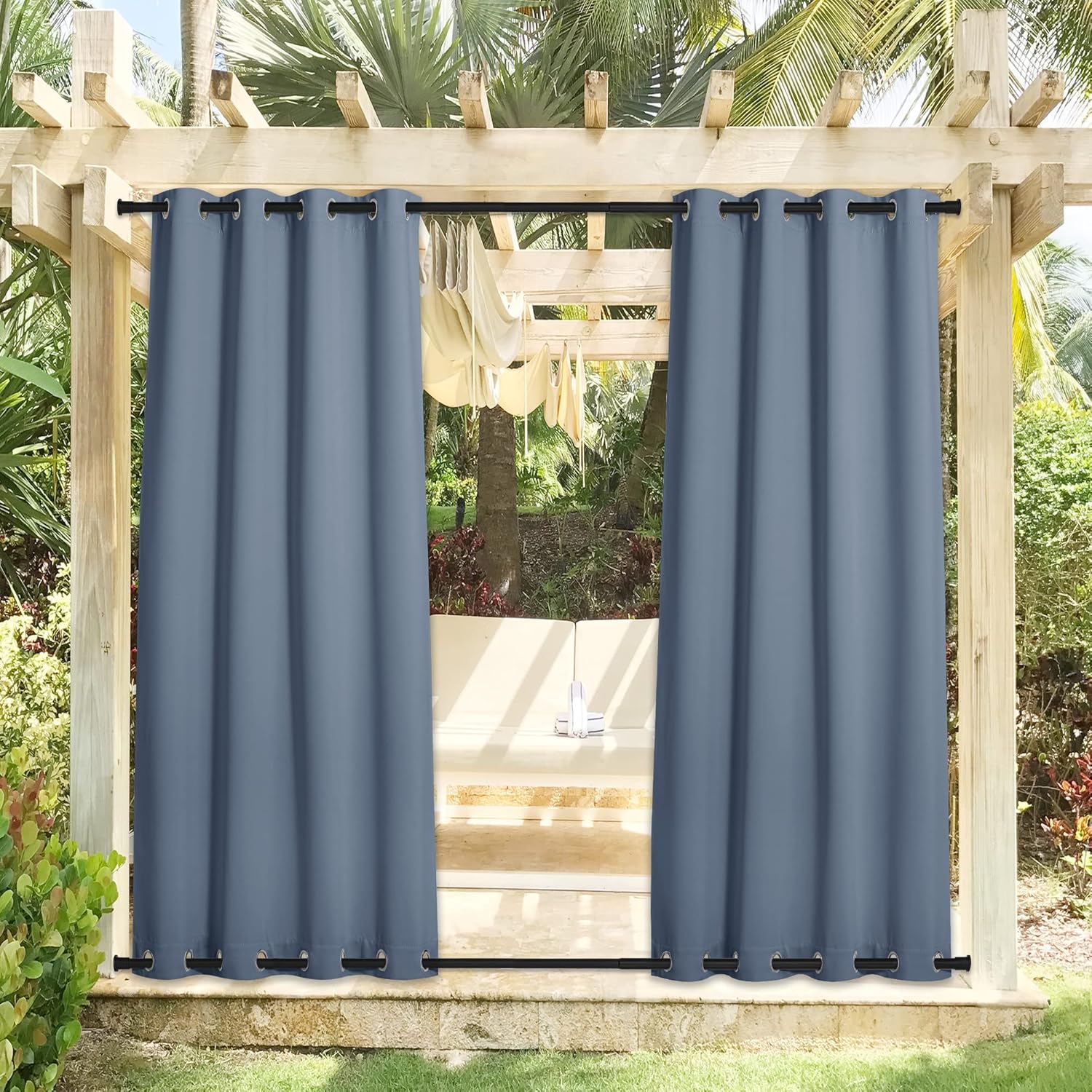 Pair of slate blue outdoor blackout curtains with top and bottom grommets, installed on a wooden patio pergola.