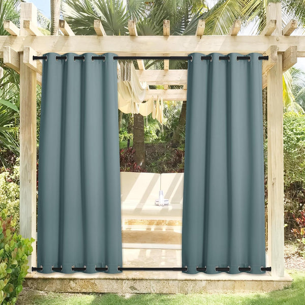 Slate blue outdoor curtains with top and bottom grommets hang on a pergola, shading a patio seating area.