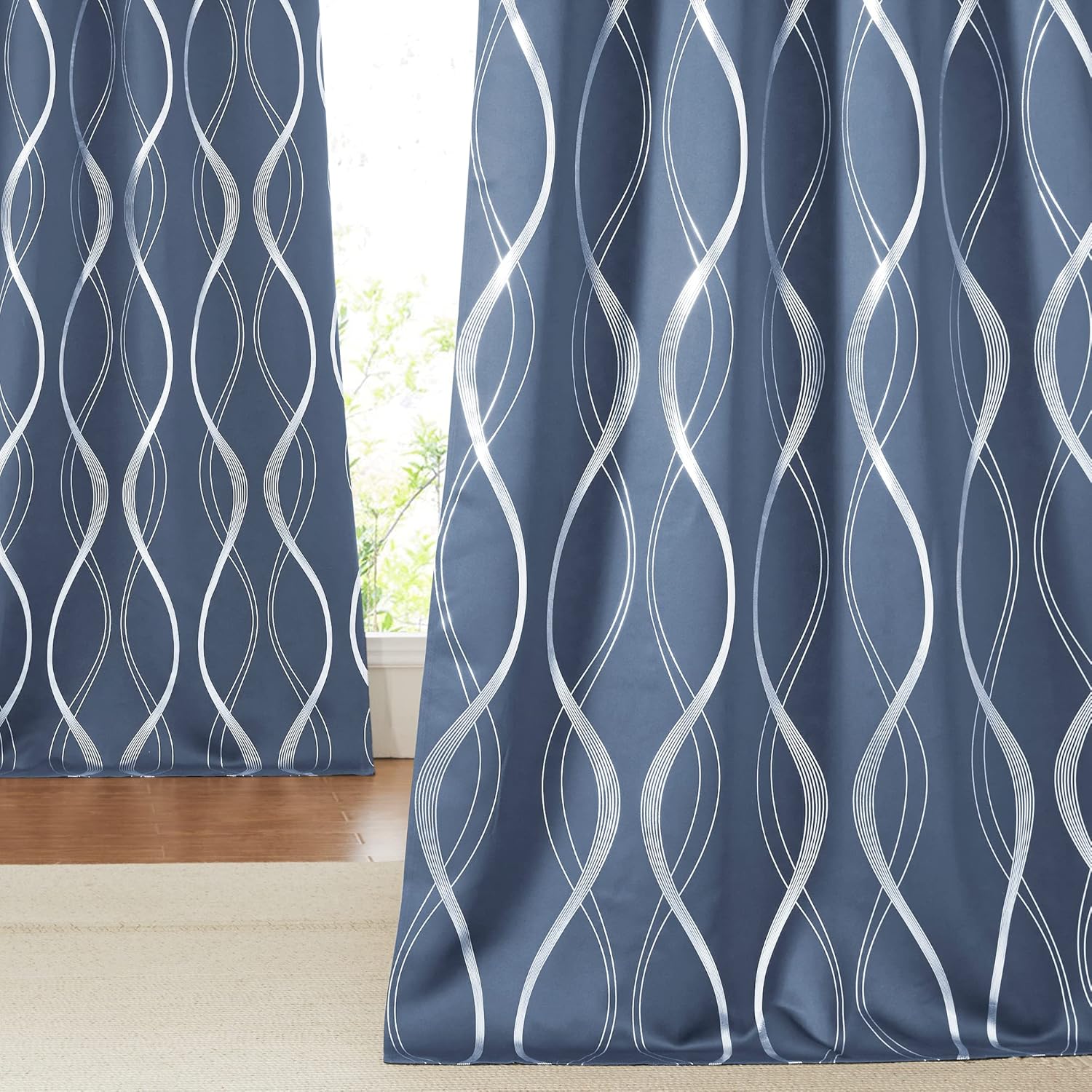 Slate blue curtains with elegant silver wavy abstract pattern, partly open, showing a bright window.
