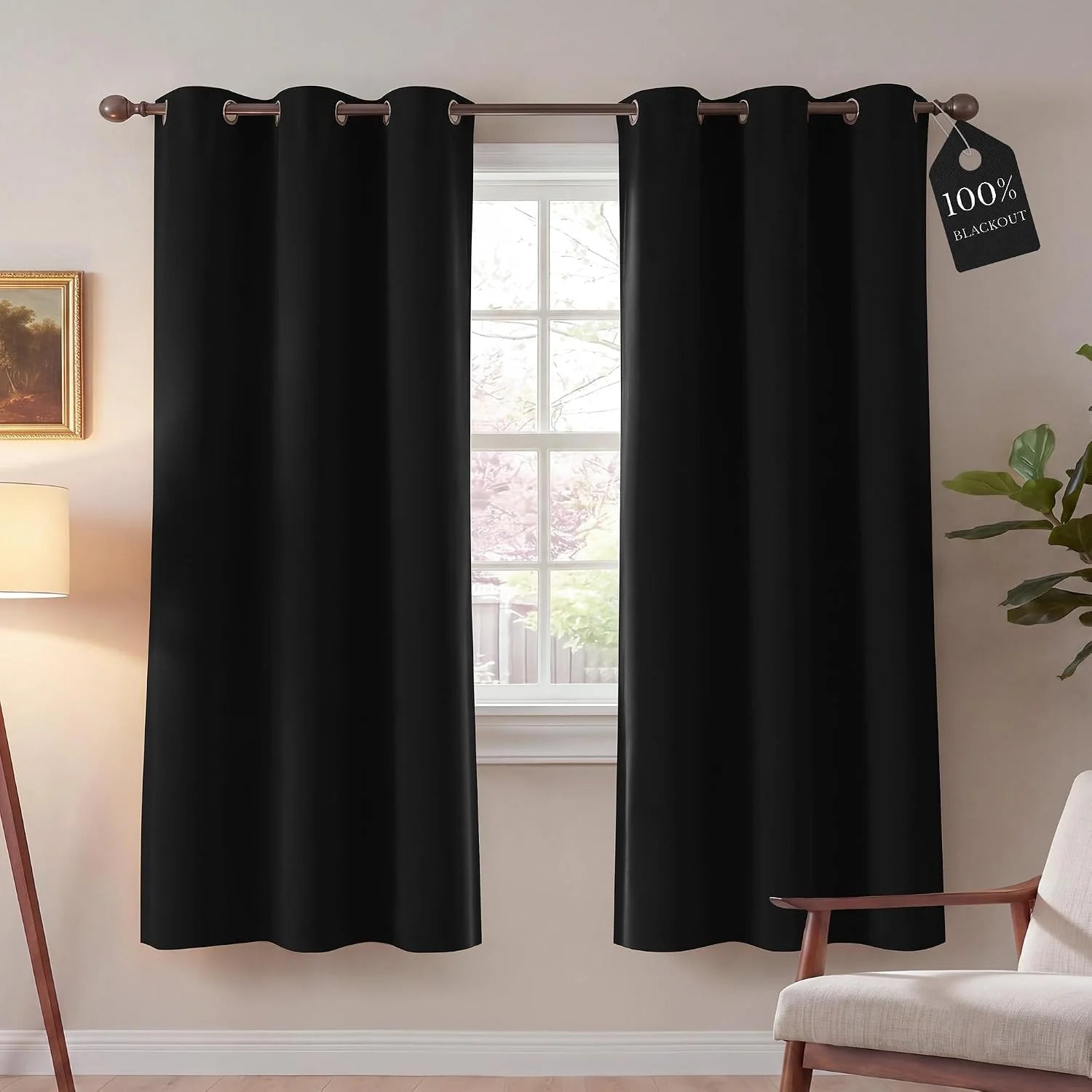 Solid black blackout curtains with grommet top in a modern room, highlighting 100% light blocking.