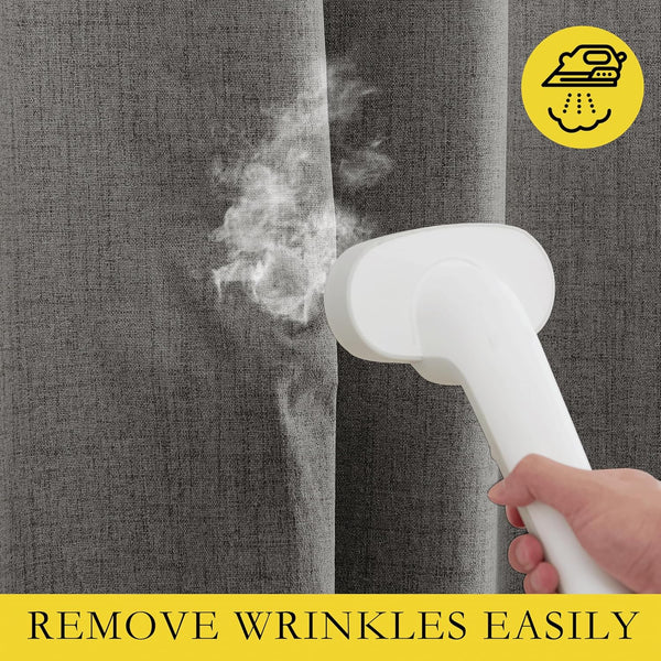 Close-up of a white handheld steamer removing wrinkles from a dark gray woven curtain.