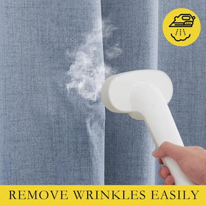 A hand holds a white handheld steamer, applying steam to a light blue textured fabric, likely a curtain, to remove wrinkles.