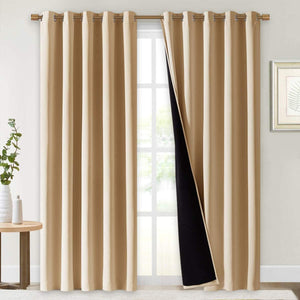 Light tan blackout curtains with metal grommet tops hang on a rod, one panel revealing its dark lining.