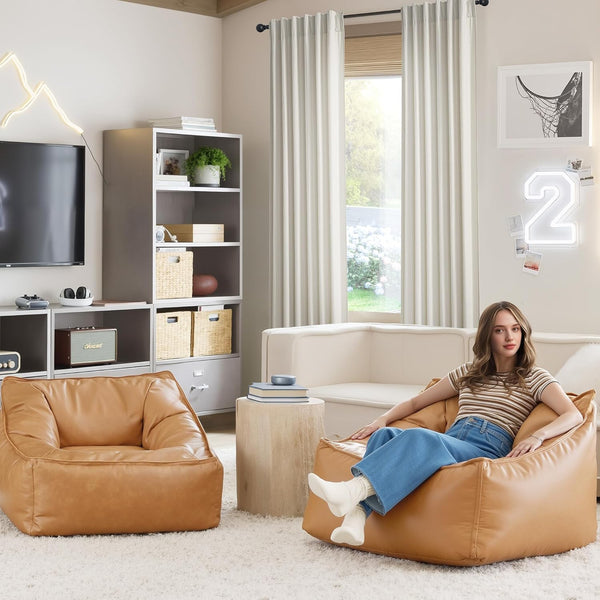 A woman relaxing comfortably in a tan faux leather square bean bag chair on a soft white shag rug in a living room.