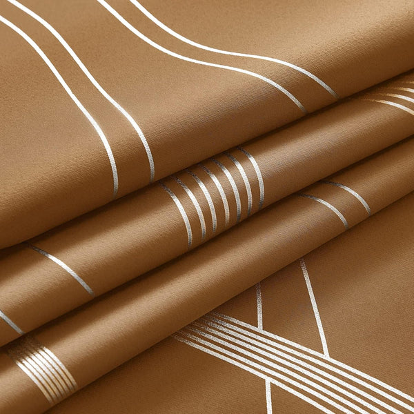 Folded tan fabric featuring a modern geometric pattern of shiny silver lines. Smooth textured curtain material.