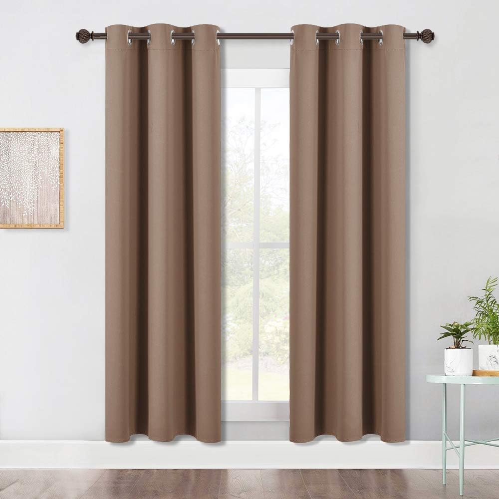 Taupe brown blackout grommet top curtains hanging on a dark rod over a window.