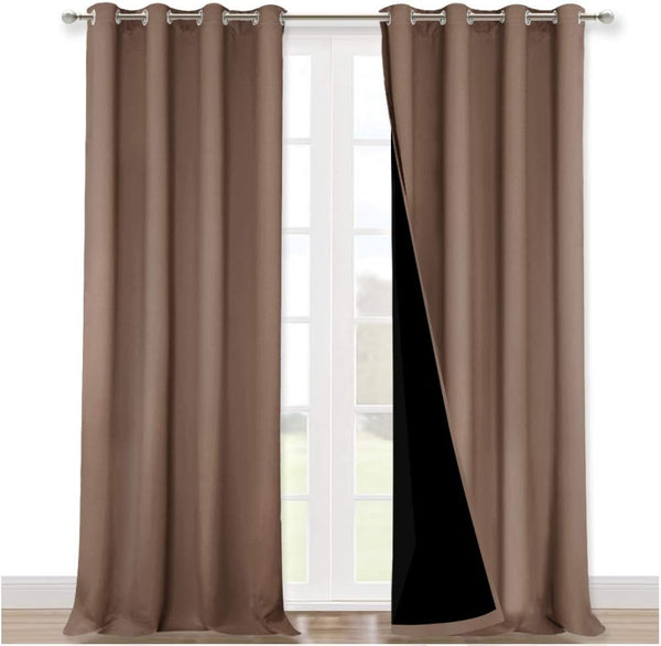Pair of taupe blackout curtains with silver grommet tops on a window rod, revealing black lining.
